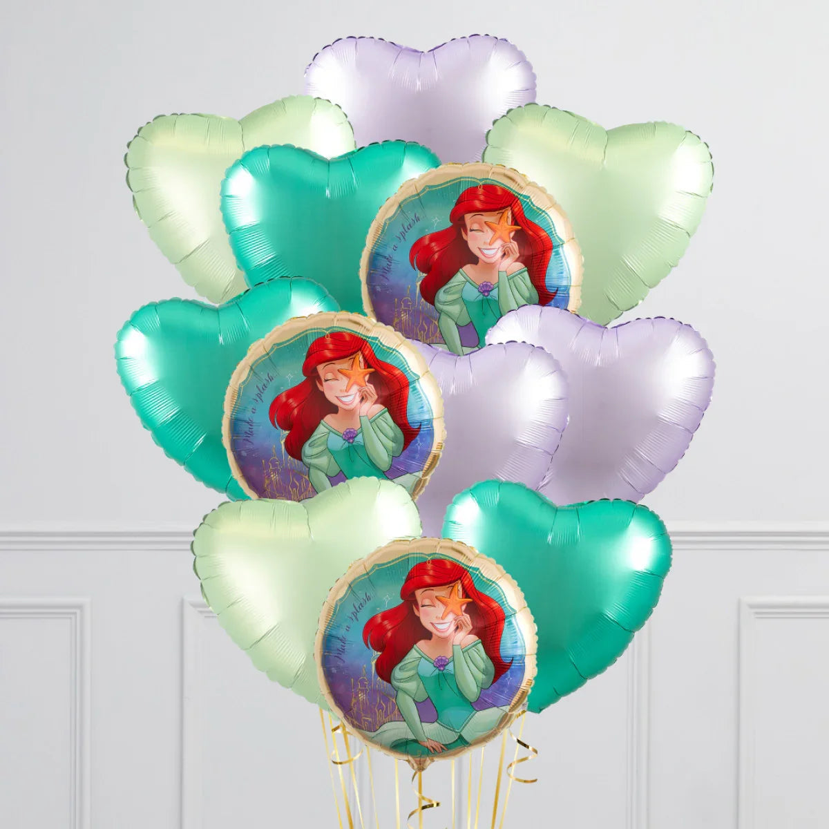 Bunch of foil balloons with The Little Mermaid and heart shapes in pastel colors against a white wall