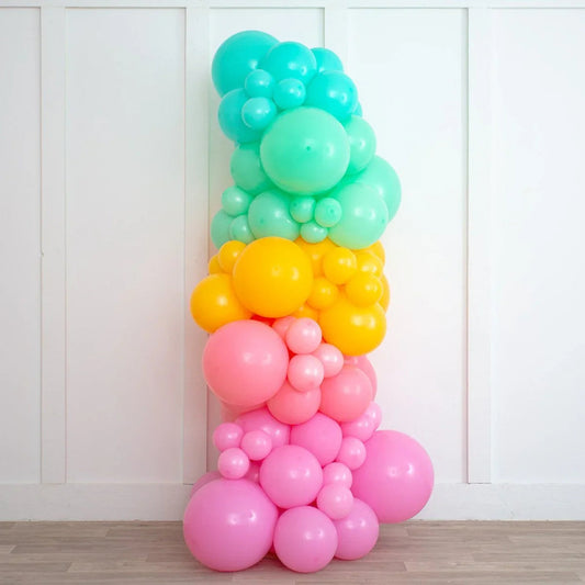 Colorful inflated balloon pillar in turquoise, yellow, coral, and pink against white wall indoors
