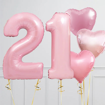 Pink foil balloons shaped as number 21 and three heart balloons with gold ribbons, celebrating 21st birthday