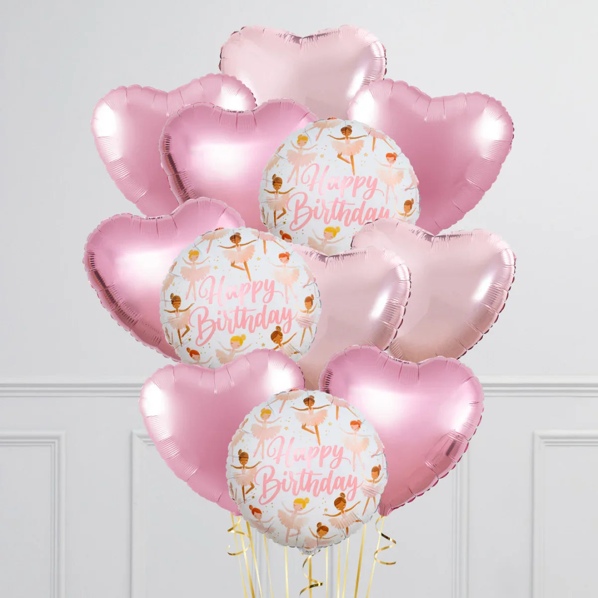 Pink heart and ballerina-themed Happy Birthday foil balloons arrangement against white wall