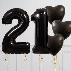 Black foil balloons shaped as number 21 and heart against white background, Dubai