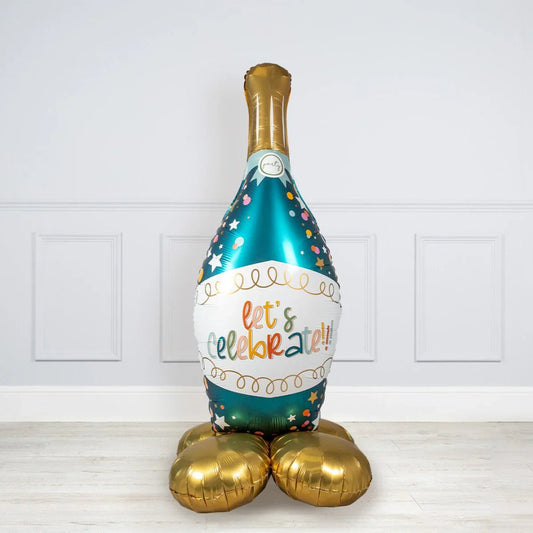 Large foil balloon shaped like a champagne bottle with colorful confetti and text 'let's celebrate' on white wall background