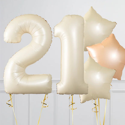 Cream colored foil balloons shaped as number 21 with star-shaped balloons in cream and peach colors