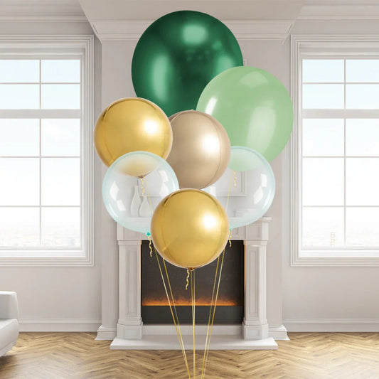 Giant forest green, gold, beige, and clear balloons in elegant modern living room with fireplace