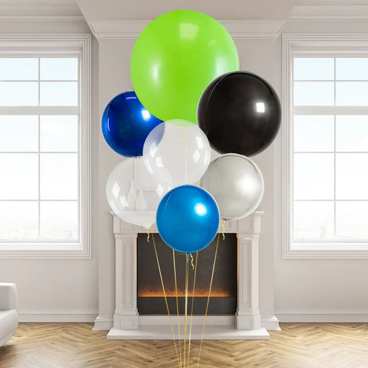 Giant helium balloons in blue, green, black, white, and silver colors in a bright modern room with fireplace