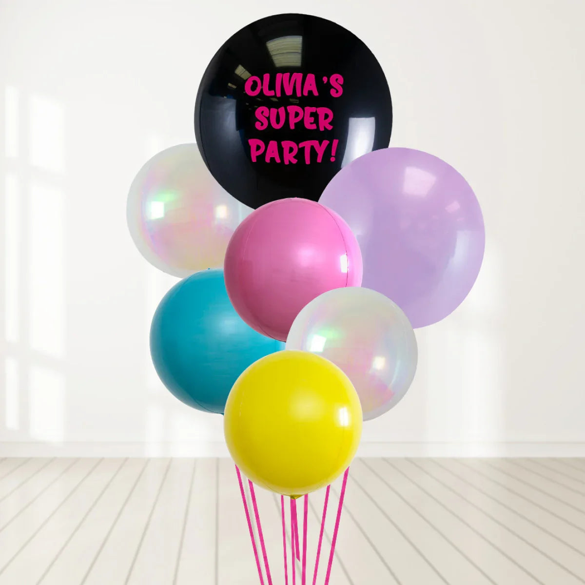Colorful party balloons bouquet with a black balloon reading Olivia's Super Party in a bright room