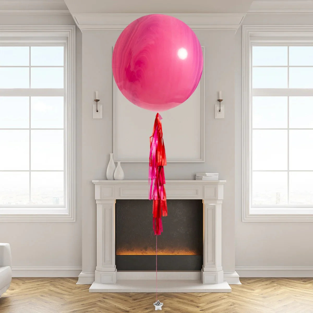 Large pink helium balloon with red tassels tied by white fireplace in modern living room