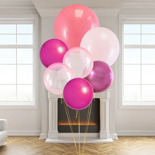 Cluster of neon pink, clear, and metallic balloons indoors by a white fireplace in bright room