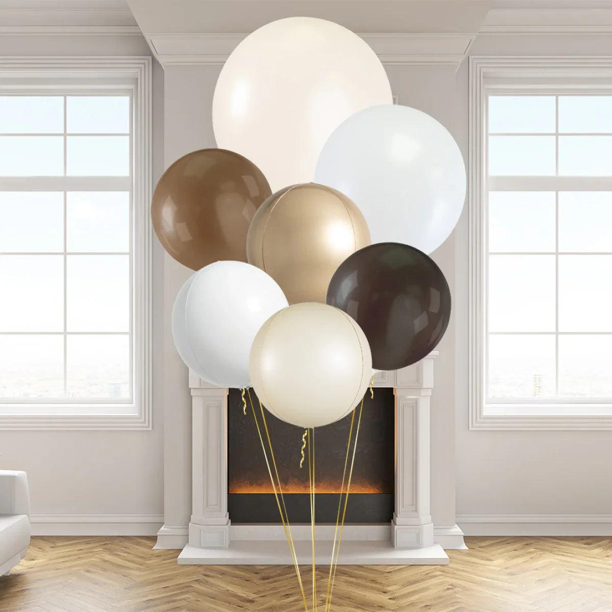 Giant neutral color balloons in beige, brown, and white shades displayed indoors by a fireplace