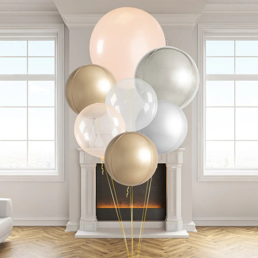 Elegant nude, blush, gold, and silver balloons in a bright room with fireplace and large windows