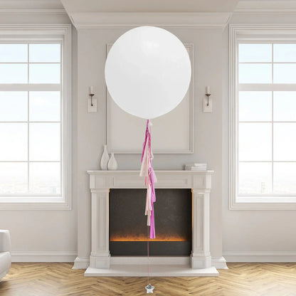 Large white helium balloon with pink and cream tassels in elegant living room with fireplace