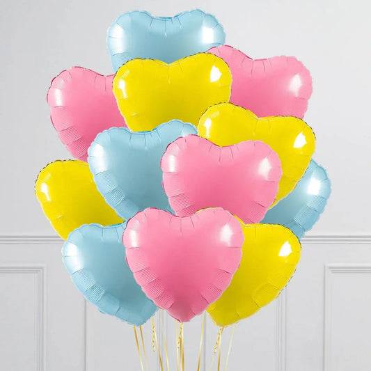 Cluster of pastel pink, yellow, and blue heart-shaped balloons with gold ribbons indoors