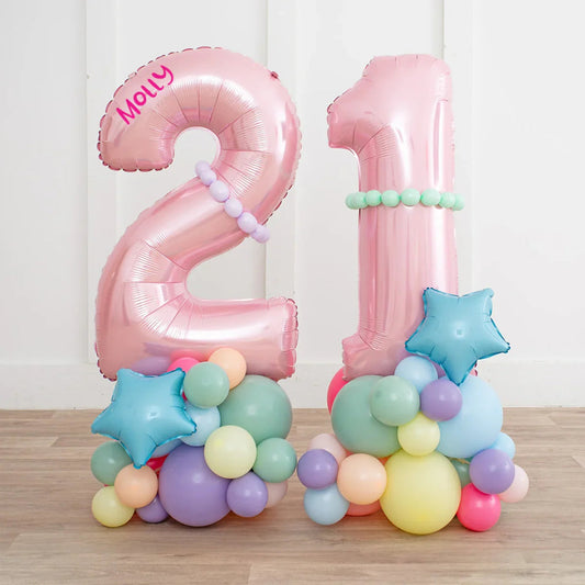Pink foil balloons shaped as numbers 2 and 1 with pastel multicolor balloon clusters and blue star balloon