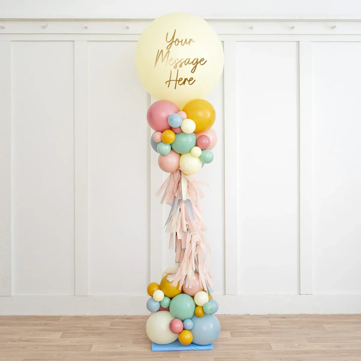 Tall balloon pillar with pastel balloons and large cream balloon on top saying 'Your Message Here'