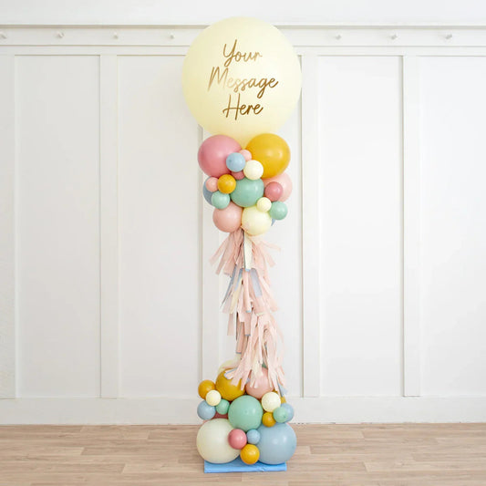 Tall balloon pillar with pastel balloons and large cream balloon on top saying 'Your Message Here'
