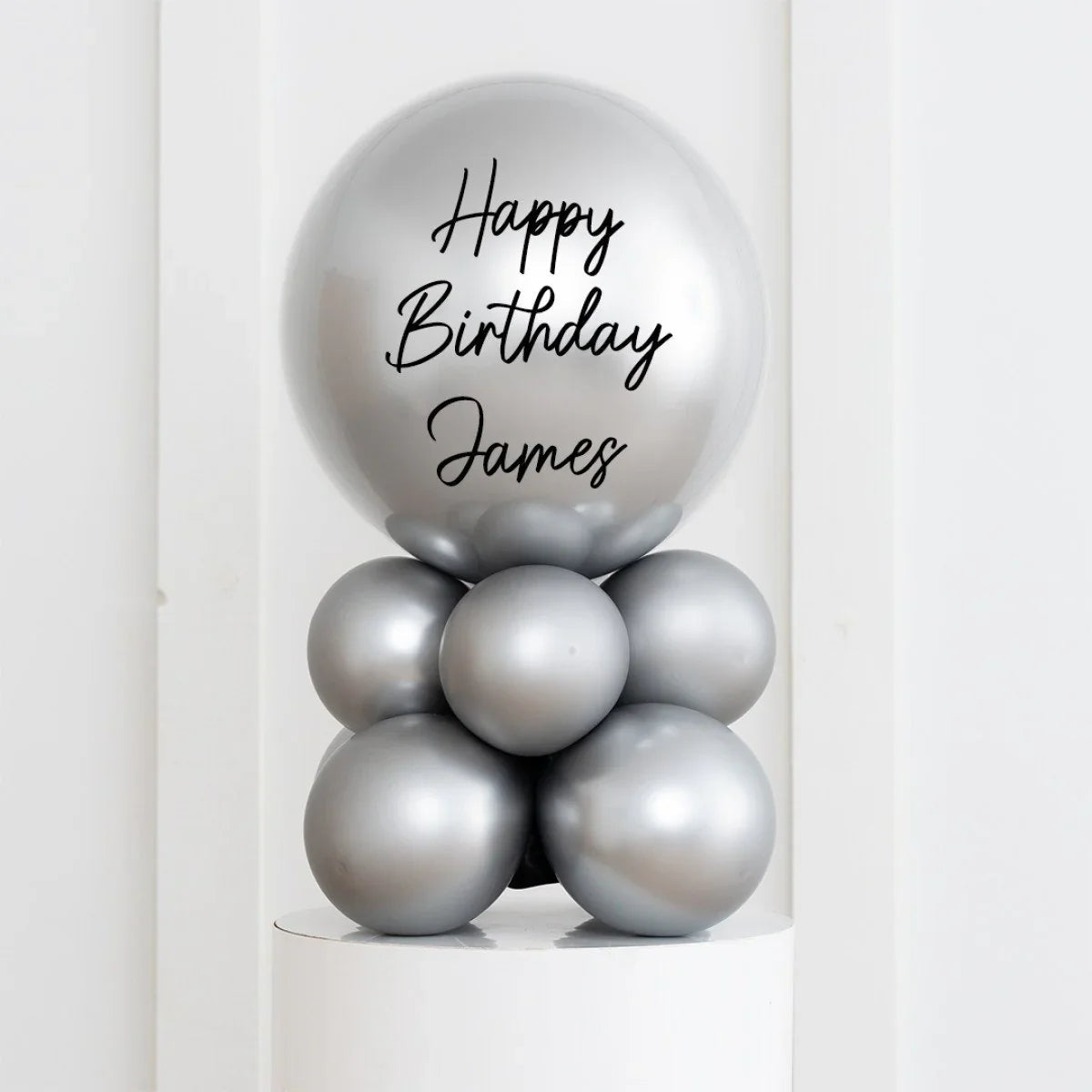 Silver chrome birthday balloon arrangement with Happy Birthday James text on top balloon