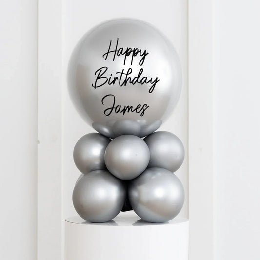 Silver chrome birthday balloon arrangement with Happy Birthday James text on top balloon