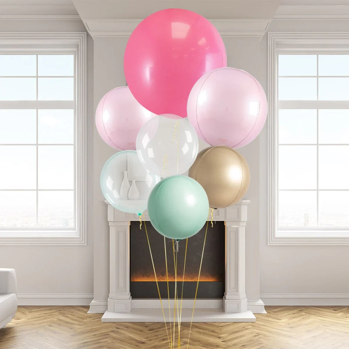 Large pink, pastel mint, gold, and transparent balloons in front of a white fireplace in a modern living room