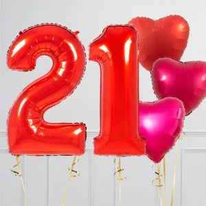 Red metallic foil balloons shaped as number 21 and heart shapes, set against a neutral background