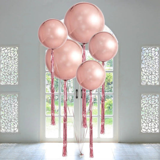 Giant rose gold orb balloons with matching tassels in bright room near white glass doors
