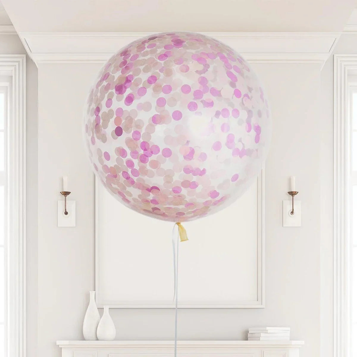 Large transparent helium balloon filled with pink and rose gold confetti in an elegant white room