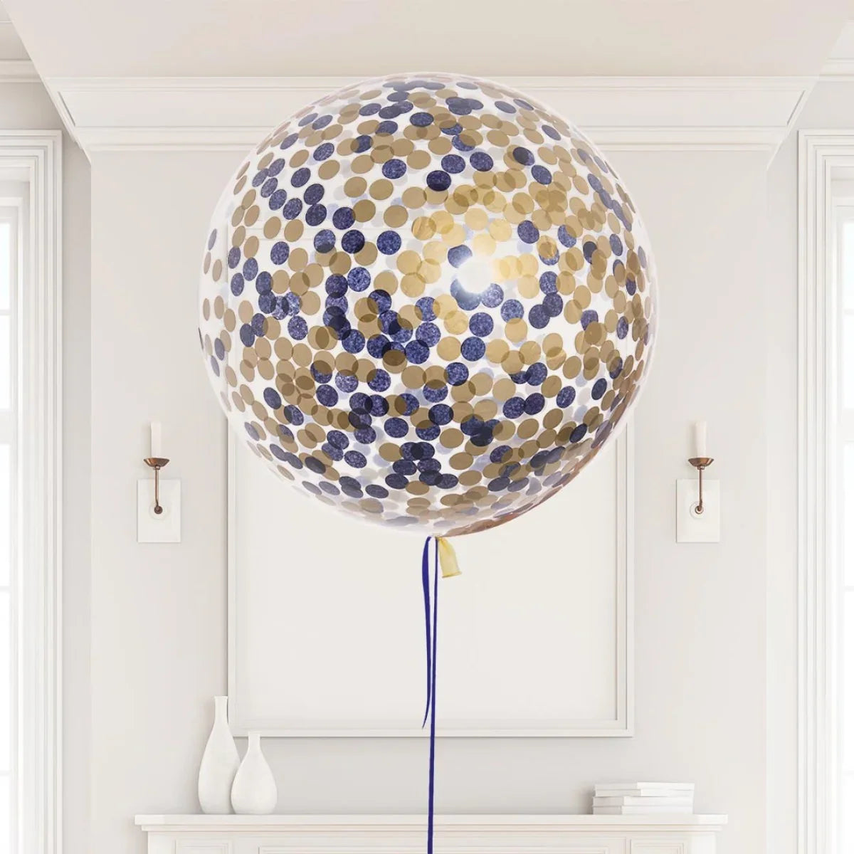 Large clear helium balloon with blue and gold confetti inside in a minimalist white room