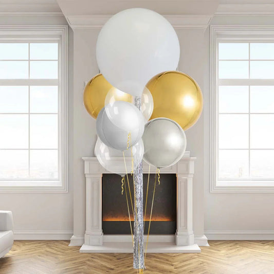 Cluster of stylish metallic gold, silver, white, and clear balloons in a modern living room with fireplace