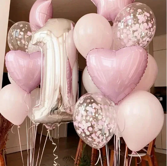 Pink and white birthday balloons including a large silver number 1 and heart-shaped balloons indoors