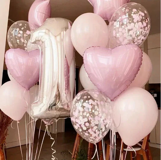 Pink and white birthday balloons including a large silver number 1 and heart-shaped balloons indoors