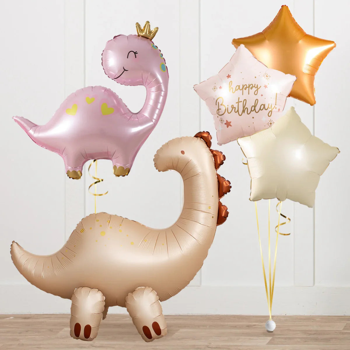 Inflatable dinosaur and star-shaped happy birthday balloons in pink, gold, and beige for party decoration