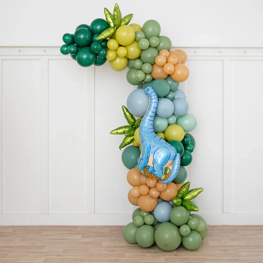 Dinosaur-themed balloon arch with green, blue, and brown balloons and a large blue dinosaur foil balloon