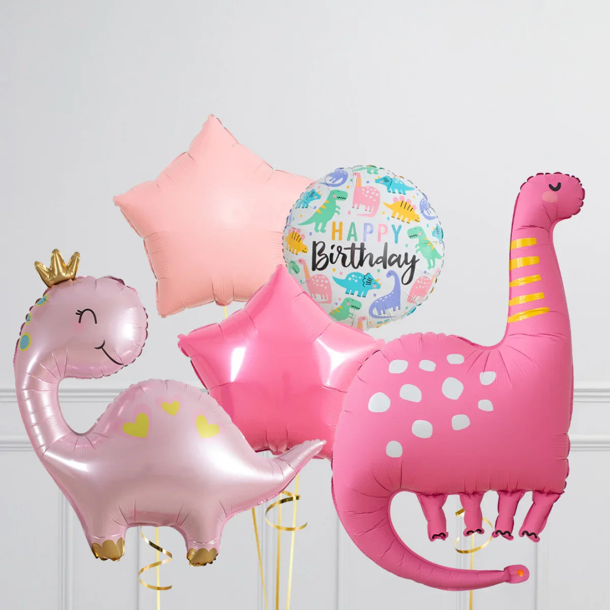 Pink dinosaur and star-shaped balloons with Happy Birthday foil balloon on white wall background