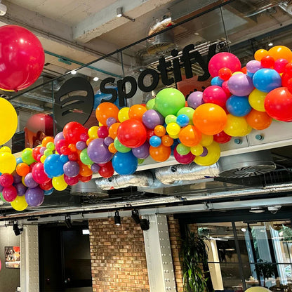 Colorful balloon garland decorating interior office space with Spotify logo on glass wall