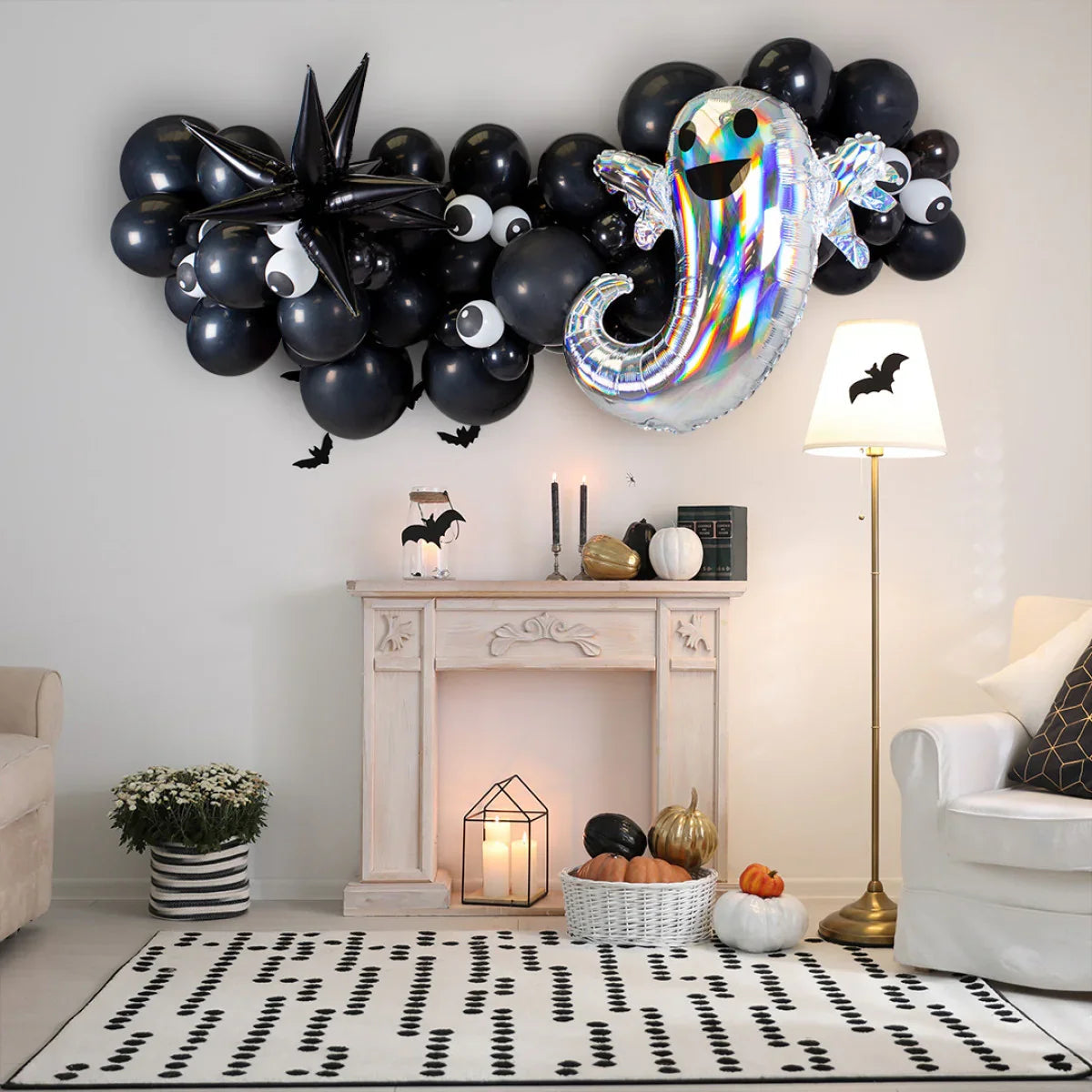 Halloween living room with black balloon garland with eyes, silver ghost balloon, pumpkins, candles, and bat decorations