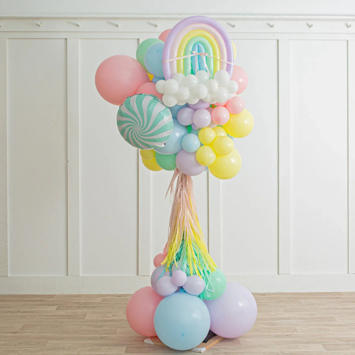 Colorful balloon arrangement with pastel rainbow and tassels indoors on wooden floor