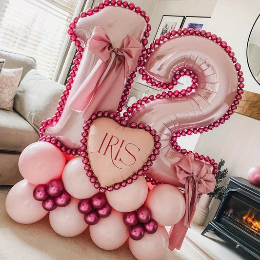 Pink metallic number 12 balloons with bows and heart-shaped balloon reading IRIS on pink and red balloon base in living room