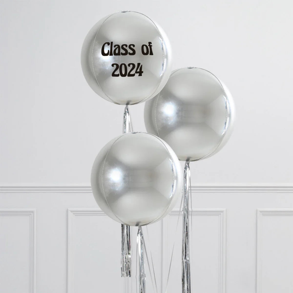 Silver helium balloons with one reading 'Class of 2024' against white wall paneling