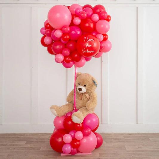 Teddy bear holding pink and red balloon bouquet with 'I love you Sabrina' message in white script