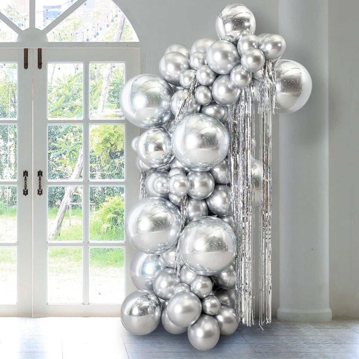 Silver chrome balloon pillar with metallic tinsel decoration near glass doors in bright room