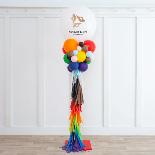 Colorful balloon garland display with tassels and large branded white balloon against white paneled wall