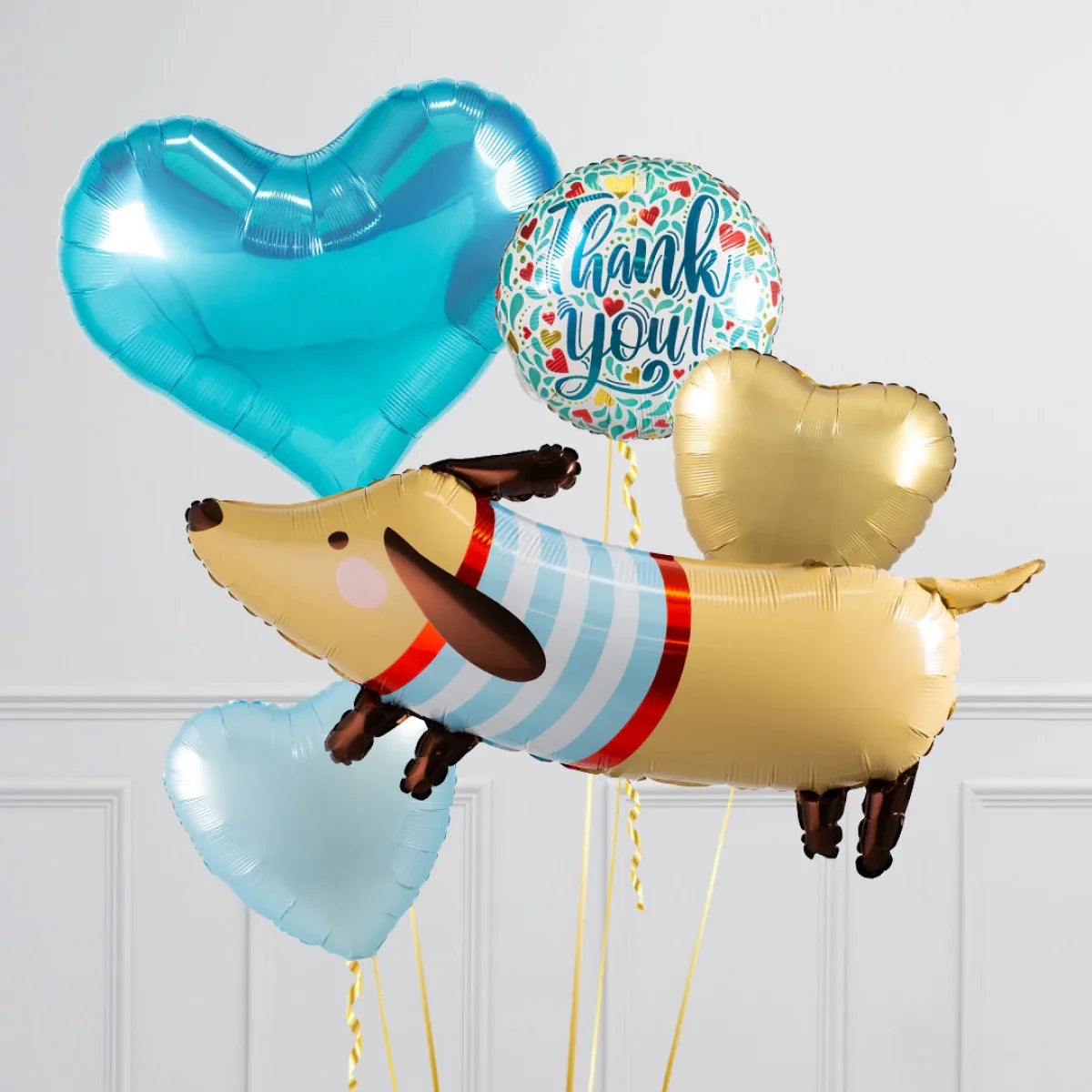Colorful foil balloons including a dog-shaped balloon, blue and gold hearts, and a round 'thank you' balloon