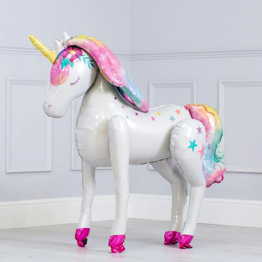 White inflatable unicorn balloon with rainbow mane, tail, yellow horn, and pink hooves standing indoors