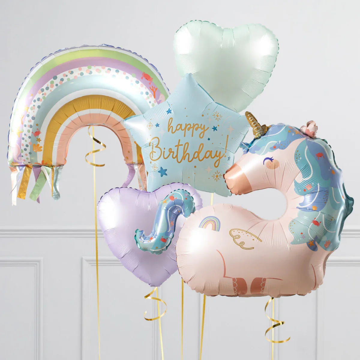 Set of pastel birthday balloons including unicorn, rainbow, star with happy birthday text, and heart shapes
