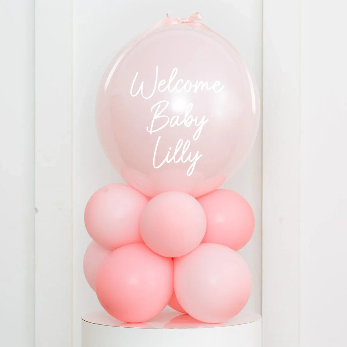 Pink balloon arrangement with large balloon reading Welcome Baby Lilly for baby shower decor