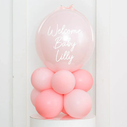 Pink balloon arrangement with large balloon reading Welcome Baby Lilly for baby shower decor